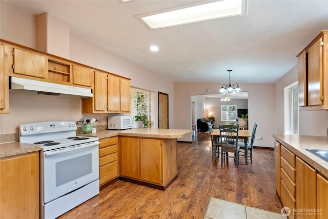 kitchen featuring a peninsula, white appliances, light countertops, and under cabinet range hood