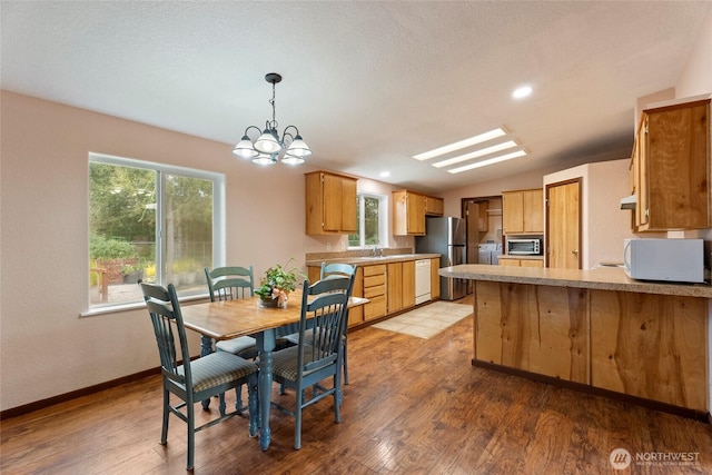 dining space with a notable chandelier, vaulted ceiling, light wood-style flooring, and baseboards