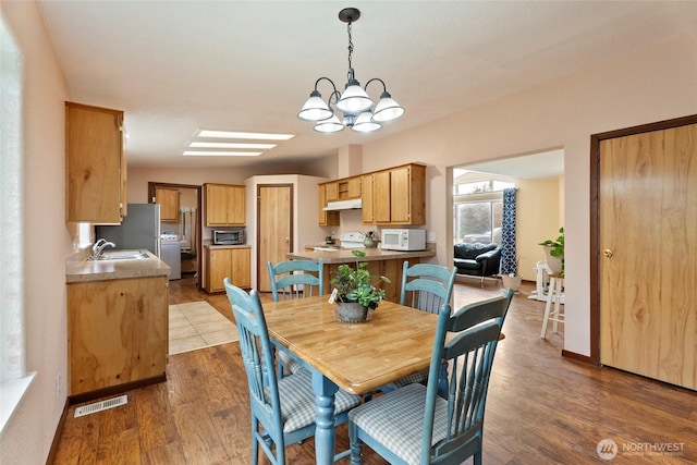 dining space featuring baseboards, a notable chandelier, visible vents, and wood finished floors