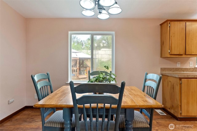 dining space featuring a chandelier, dark wood-type flooring, visible vents, and baseboards