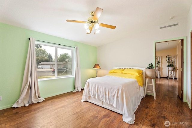 bedroom with visible vents, baseboards, and wood finished floors