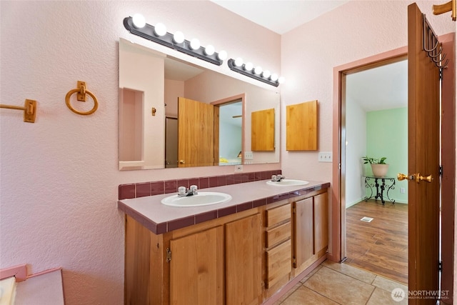 full bath featuring tile patterned flooring, a sink, and double vanity