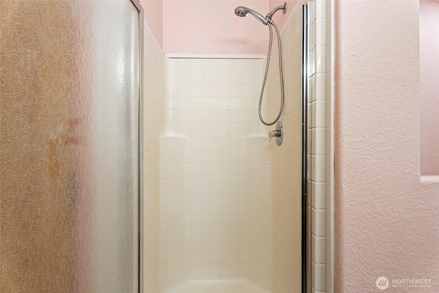 bathroom with a stall shower and a textured wall