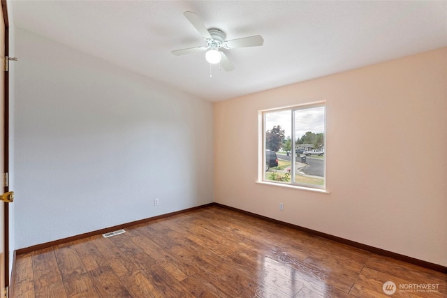 unfurnished room with a ceiling fan, wood-type flooring, visible vents, and baseboards