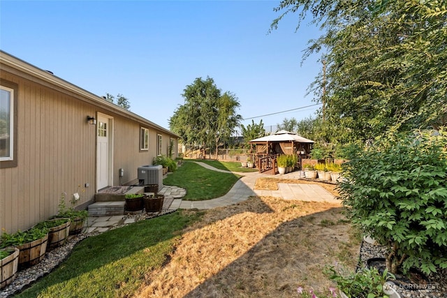 view of yard featuring fence, central AC unit, and a gazebo