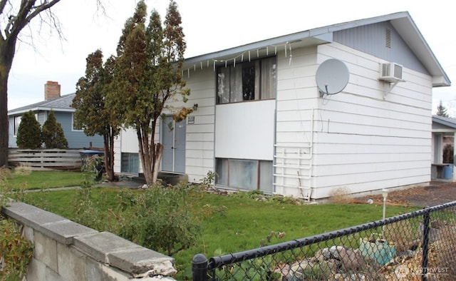 view of home's exterior featuring a wall unit AC, fence, and a yard