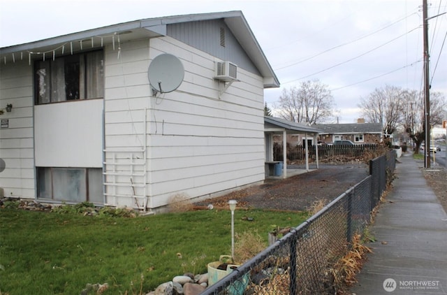 view of home's exterior featuring a wall unit AC, fence, and a lawn