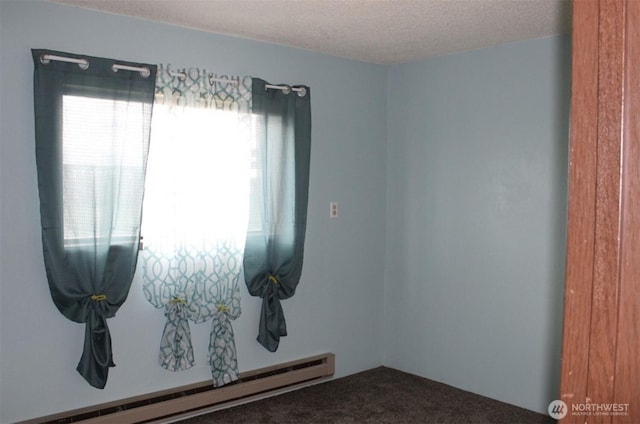 empty room with a baseboard heating unit, a textured ceiling, and carpet flooring