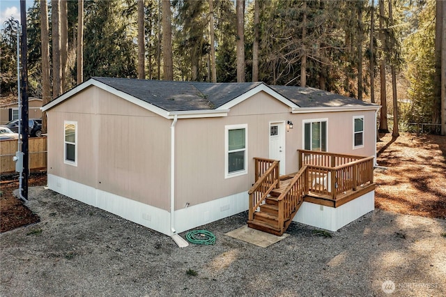 manufactured / mobile home with roof with shingles, crawl space, a wooden deck, and fence