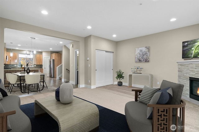 living area featuring recessed lighting, a stone fireplace, and baseboards