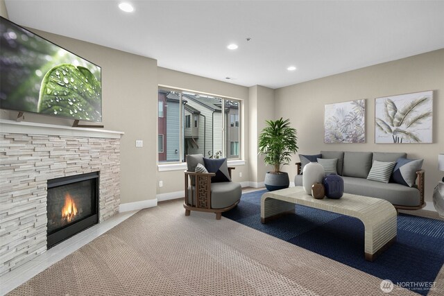 carpeted living room featuring recessed lighting, a stone fireplace, and baseboards