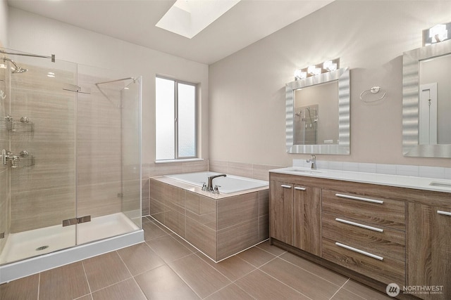 full bath featuring a skylight, a sink, a bath, double vanity, and a stall shower