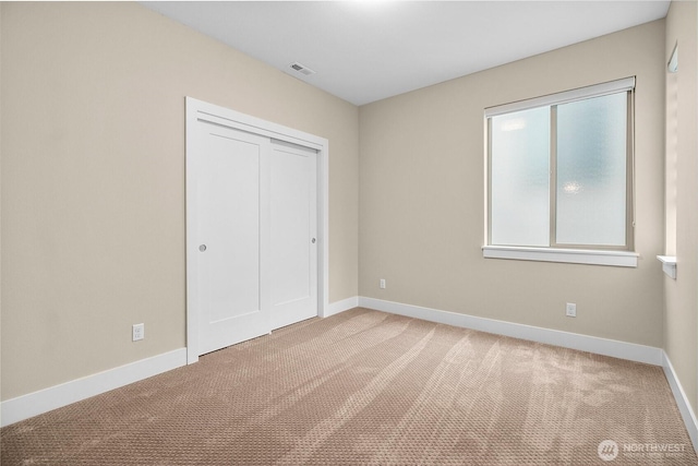 unfurnished bedroom with carpet floors, a closet, visible vents, and baseboards