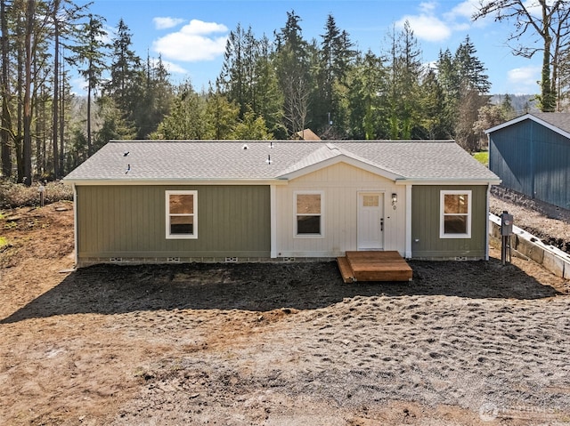 view of front facade with crawl space, a shingled roof, and fence