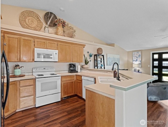 kitchen featuring white appliances, dark wood finished floors, a peninsula, vaulted ceiling, and a sink