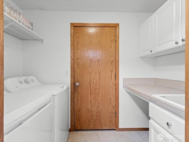 clothes washing area featuring separate washer and dryer, a sink, cabinet space, and baseboards