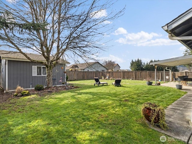 view of yard featuring an outbuilding, a patio area, and a fenced backyard