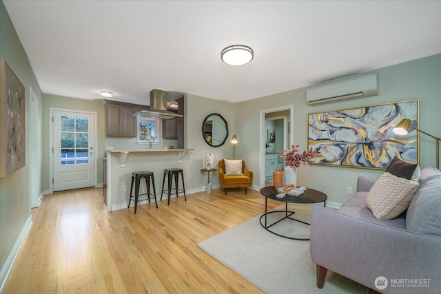 living room featuring baseboards, a wall mounted air conditioner, and light wood finished floors