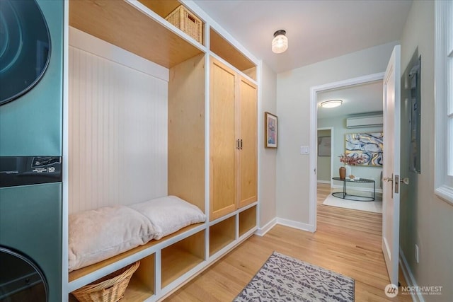 mudroom with light wood-type flooring, a wall unit AC, visible vents, and baseboards