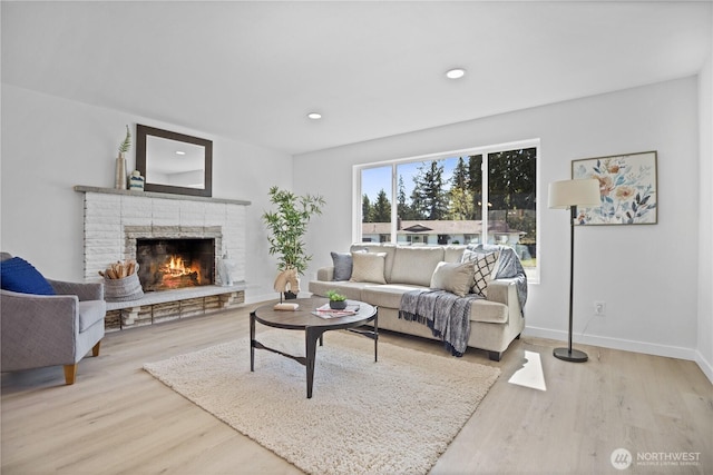 living room featuring a lit fireplace, recessed lighting, wood finished floors, and baseboards