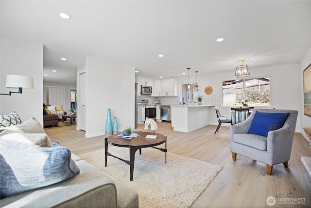 living area featuring baseboards, light wood finished floors, and recessed lighting