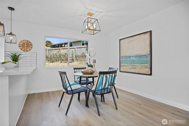 dining area featuring a notable chandelier, baseboards, and wood finished floors