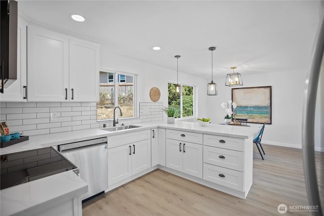 kitchen featuring a peninsula, a sink, white cabinetry, appliances with stainless steel finishes, and decorative backsplash