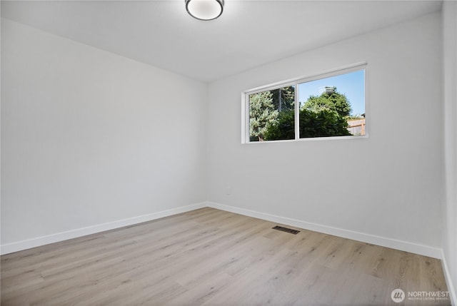 spare room featuring baseboards, visible vents, and light wood finished floors