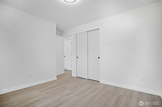 unfurnished bedroom with a closet, baseboards, and wood finished floors