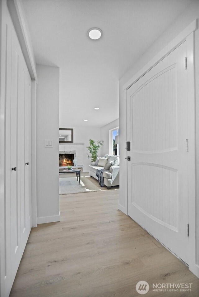 foyer entrance with a warm lit fireplace and light wood finished floors