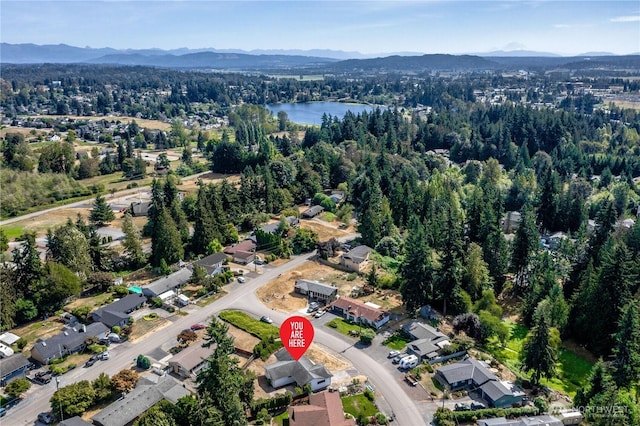 aerial view featuring a wooded view and a water and mountain view