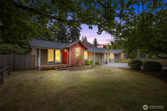 view of front of property with concrete driveway, fence, and a lawn