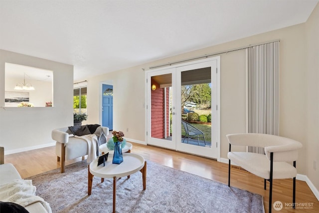 living room with a chandelier, french doors, wood finished floors, and baseboards