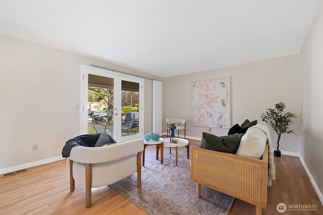 living room with french doors, visible vents, baseboards, and wood finished floors