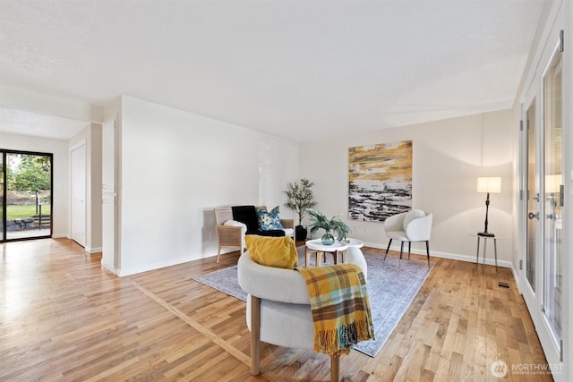 living area featuring baseboards, visible vents, and light wood-style floors