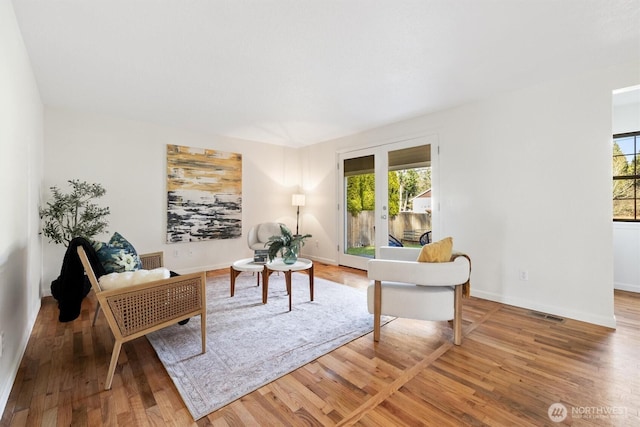 sitting room with french doors, visible vents, baseboards, and wood finished floors