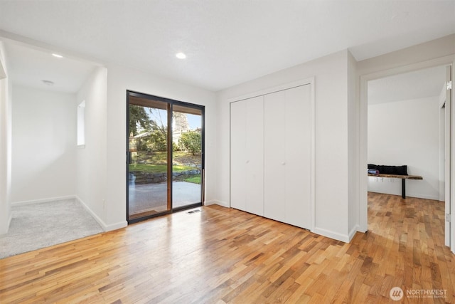 unfurnished bedroom featuring light wood finished floors, a closet, visible vents, access to outside, and baseboards