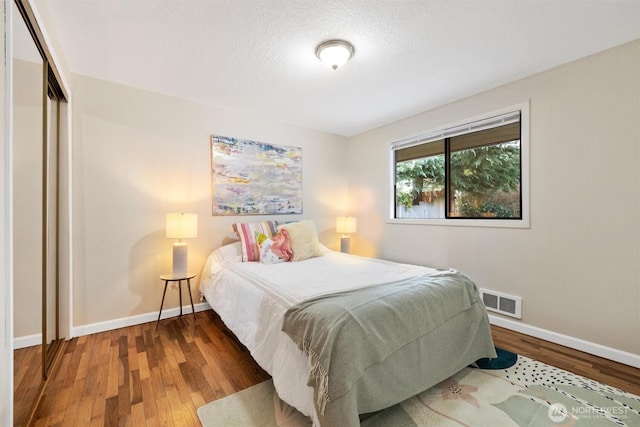 bedroom featuring wood finished floors, visible vents, and baseboards