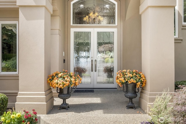 view of exterior entry featuring french doors and stucco siding