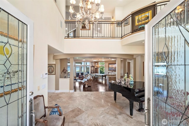 entryway with baseboards, a high ceiling, and an inviting chandelier