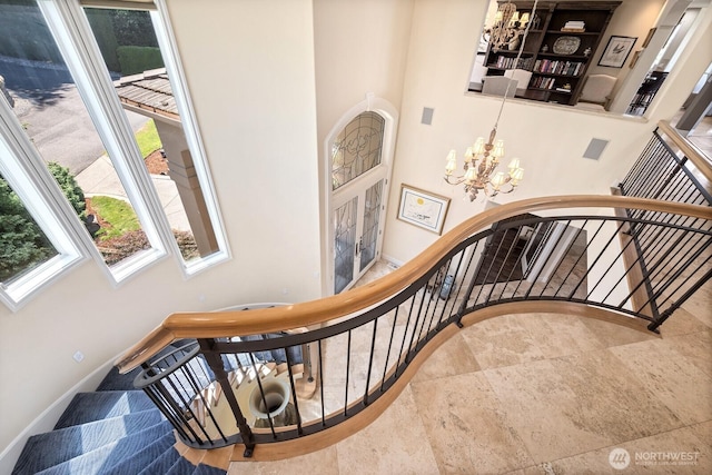 staircase with a healthy amount of sunlight, baseboards, and a chandelier