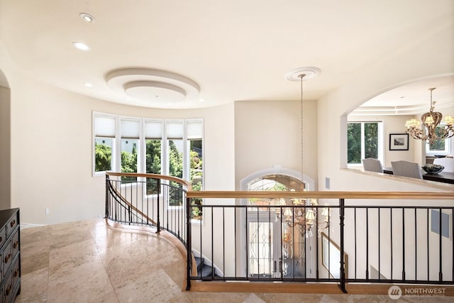 hall featuring arched walkways, recessed lighting, an upstairs landing, and an inviting chandelier