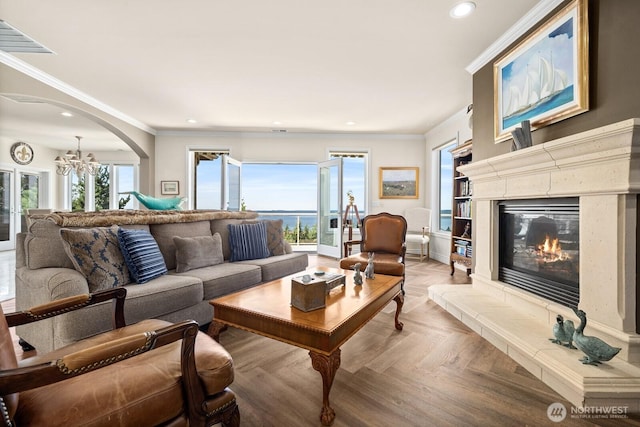 living room with recessed lighting, a notable chandelier, crown molding, and a high end fireplace