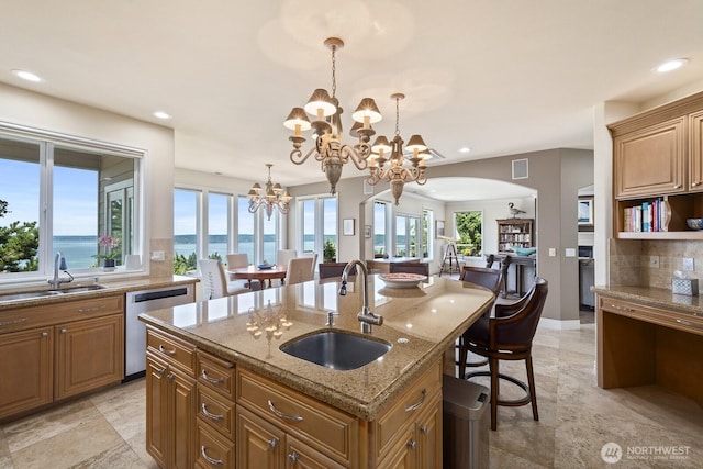 kitchen with dishwasher, stone countertops, a sink, and a chandelier