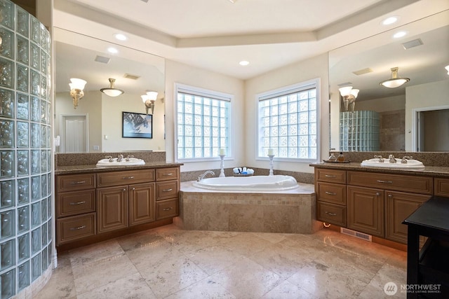 full bath featuring a tray ceiling, a sink, and a bath