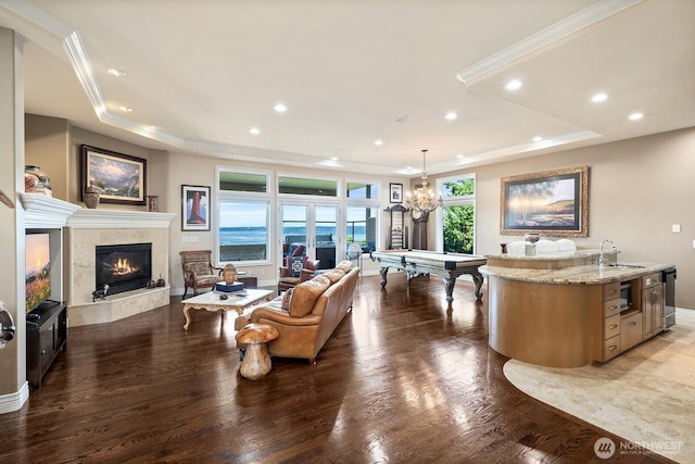 living room featuring a tray ceiling, a tiled fireplace, and ornamental molding