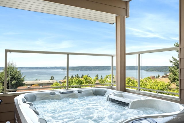 balcony featuring a water view and a hot tub