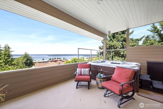 view of patio with a water view and a hot tub