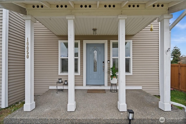 entrance to property with a porch and fence