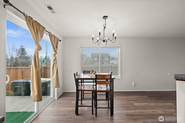 dining space featuring a chandelier, visible vents, baseboards, and wood finished floors